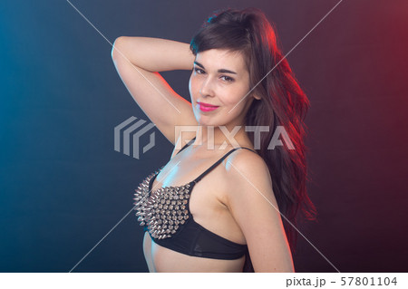 Attractive young sexy brunette woman in riveted top posing in the studio on a dark background 57801104