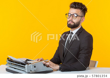 Arab businessman or manager in formal suit typing text on a typewriter on a yellow background Arab businessman or manager in formal suit typing text on a typewriter on a yellow background 57801354