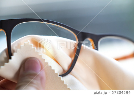 Woman's hand cleaning black eyeglasses by microfibre cleaning cloths, Close up & Macro shot, Selective focus, Optical concept 57804594