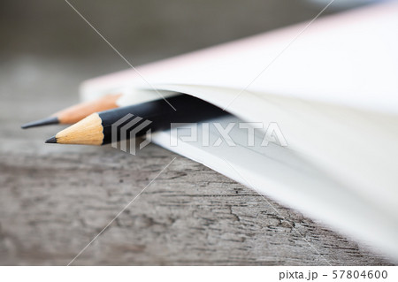 Black and white pencils  sandwich between white notebook on wood background, Close up & Macro shot, Selective focus, Stationery concept 57804600