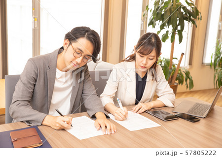 オフィスで紙に書き込みをする男女のビジネスマン オフィスで紙に書き込みをする男女のビジネスマン 57805222