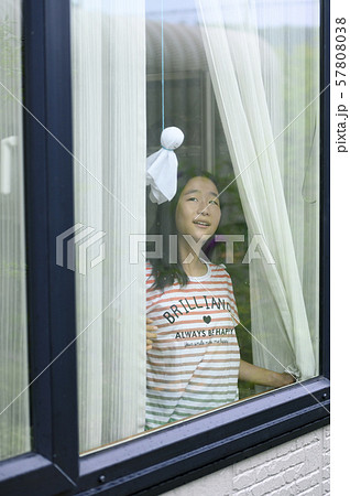 窓から雨の様子を見る子ども（降り止む） 57808038