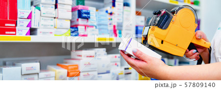 pharmacist using yellow labeling gun for sticking price label of medicine in pharmacy  57809140