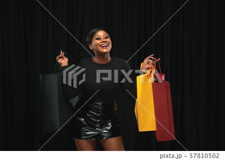 Young woman in dress shopping on black background 57810502