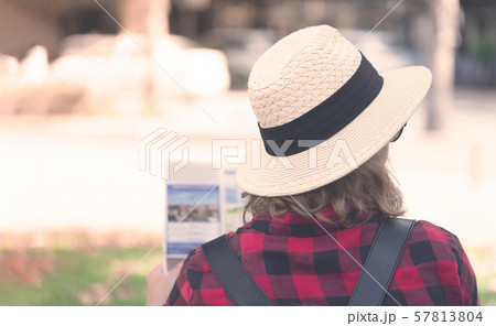 A young woman with a backpack reading a map A young woman with a backpack reading a map 57813804