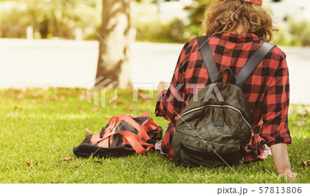 A young woman with a backpack sitting on the grass A young woman with a backpack sitting on the grass 57813806