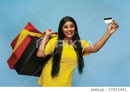 Young woman in dress shopping on blue background Young woman in dress shopping on blue background 57815491