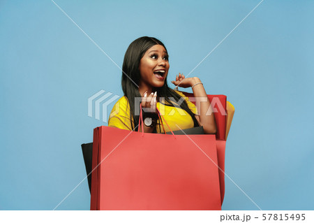 Young woman in dress shopping on blue background 57815495