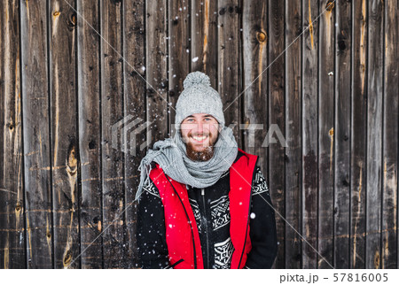 Young man standing against wooden background outdoors in winter. Young man standing against wooden background outdoors in winter. 57816005