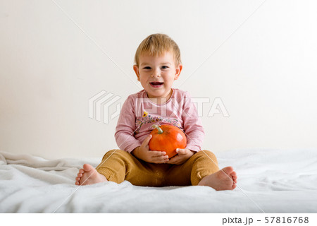 Cute little girl hugging a pumpkin on a bed indoors. copy space Cute little girl hugging a pumpkin on a bed indoors. copy space 57816768