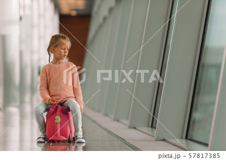 Adorable little girl in airport with her luggage waiting for boarding Adorable little girl in airport with her luggage waiting for boarding 57817385