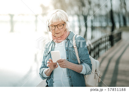 Focused vigorous dame in massive headsets holding a music player 57851188