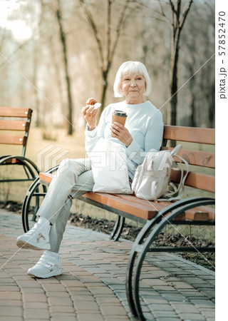 Cheerful beautiful aged dame tasting of coffee and cake 57852470