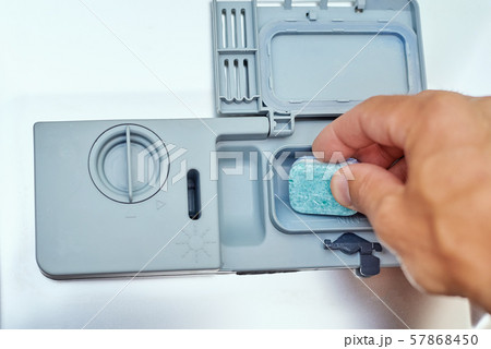 Hand putting soap tablet in dishwasher machine, close up. Kitchen domestic appliance concept Hand putting soap tablet in dishwasher machine, close up. Kitchen domestic appliance concept 57868450