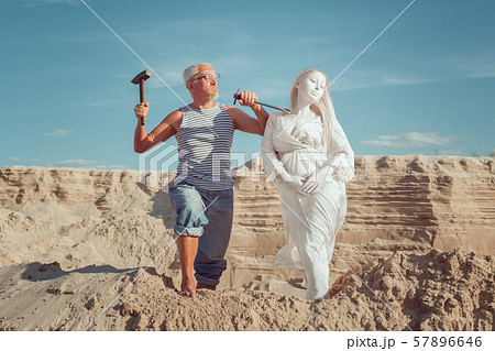 Old man makes a statue of a woman. 57896646