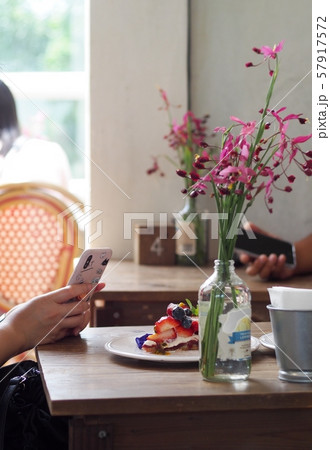 hands of an asian girl holding mobile phone on a wooden table in coffee shop trying to take photo of fruit cake with smart phone to share on social media profile as contemporary youth lifestyle hands of an asian girl holding mobile phone on a wooden table in coffee shop trying to take photo of fruit cake with smart phone to share on social media profile as contemporary youth lifestyle 57917572