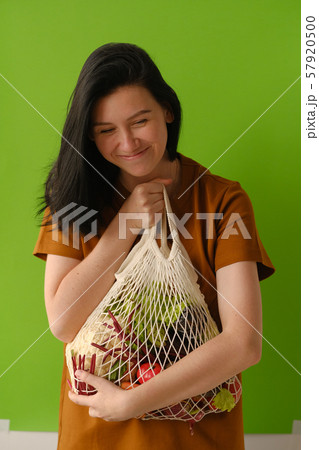 Young woman holds string bag mesh with vegetables 57920500