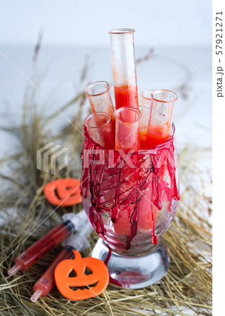 Halloween bloody glass with test tubes of tomato juice . Party drinks on dry grass 57921271