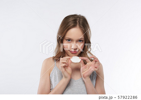 Charming teen girl in gray tank top holding cotton pad 57922286
