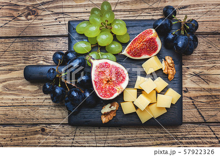 Cheese cubes, fresh fruit figs grapes Honey walnut on wooden chopping Board. Copy space. 57922326