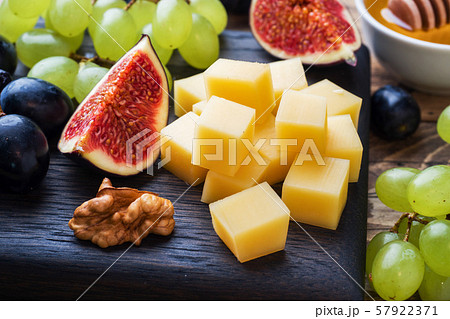 Cheese cubes, fresh fruit figs grapes Honey walnut on wooden chopping Board. Selective focus. Close up. 57922371