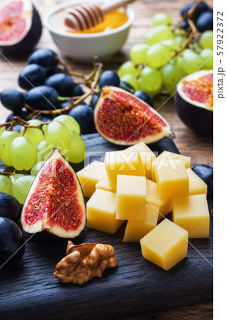 Cheese cubes, fresh fruit figs grapes Honey walnut on wooden chopping Board. Selective focus. Close up. 57922372