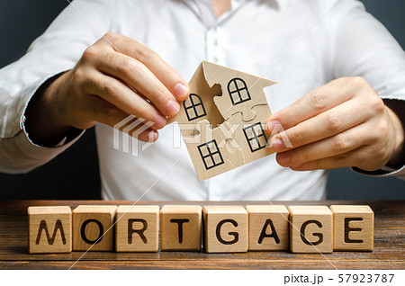 A man collects a house from the puzzles over the inscription Mortgage. Construction of your own residential building. Buying a home on credit loan, improvement of living conditions 57923787