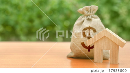 Wooden house figurine and money bag with a dollar symbol. Budget, subsidized funds. Mortgage loan for purchase housing, construction or modernization. Tax, building maintenance. Wooden house figurine and money bag with a dollar symbol. Budget, subsidized funds. Mortgage loan for purchase housing, construction or modernization. Tax, building maintenance. 57923800