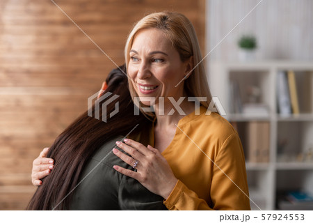 Smiling blonde psychologist hugging her patient after consultation in cabinet 57924553