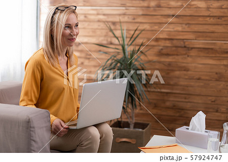 Beautiful psychologist holding laptop on knees in private consulting room 57924747