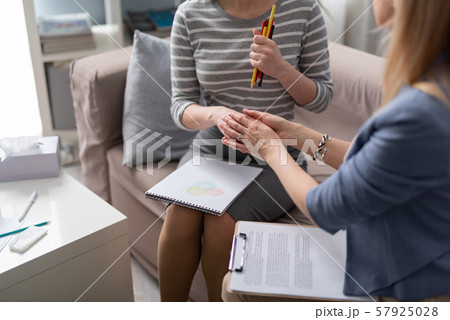 Cropped photo of female psychologist holding her client's hand during the seance 57925028