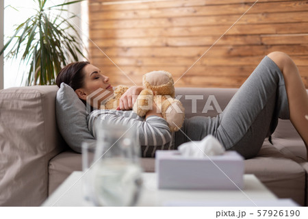 Brunette Caucasian woman lying on sofa with toy in arms 57926190