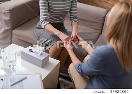 High angle of blonde female psychologist holding client arms during seance High angle of blonde female psychologist holding client arms during seance 57926366