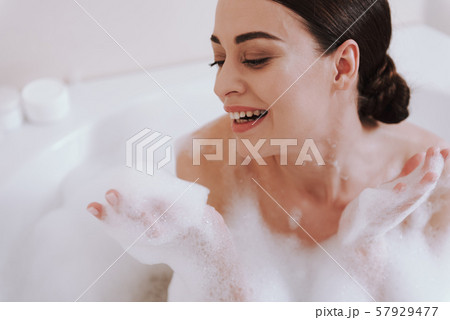 Joyful young woman enjoying her bath procedure 57929477
