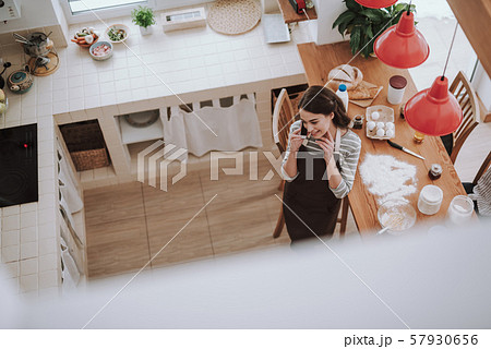 Smiling woman is talking on phone while cooking pastry 57930656