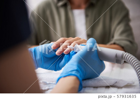 Manicurist removing cuticle on lady fingers with electric nail mill 57931635