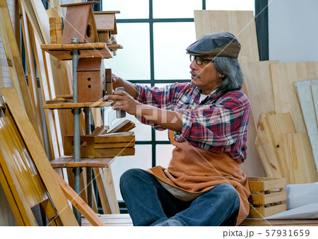Asian old craftsman set up his wood product on shelf in the work space 57931659