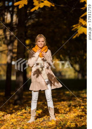 Portrait of pretty blonde teen girl having fun in autumn park near tree with yellow leaves 57931759