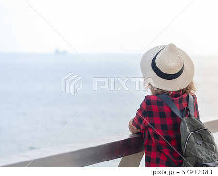 A young woman with a backpack staying on the walk A young woman with a backpack staying on the walk 57932083