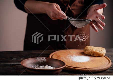 Woman sprinkling flour on gingerbread dough Woman sprinkling flour on gingerbread dough 57935678