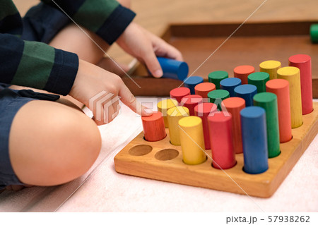 Closeup: Hands of a little Montessori kid (3-6) learning about size, orders, sorting, arranging by engaged colorful wooden sensorial blocks. Educational toys, Cognitive skills, Montessori activity. Closeup: Hands of a little Montessori kid (3-6) learning about size, orders, sorting, arranging by engaged colorful wooden sensorial blocks. Educational toys, Cognitive skills, Montessori activity. 57938262