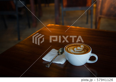 Hot art Latte Coffee in a cup on wooden table and Coffee shop blur background Hot art Latte Coffee in a cup on wooden table and Coffee shop blur background 57941126