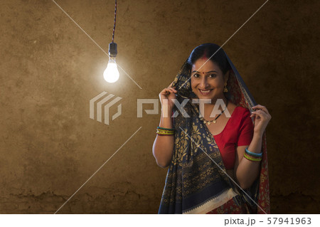 Portrait of rural woman standing against light bulb in house 57941963