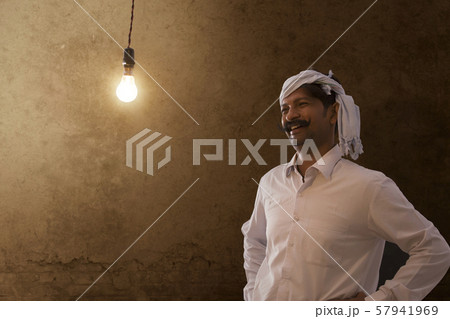 Happy farmer looking at light bulb in his house 57941969