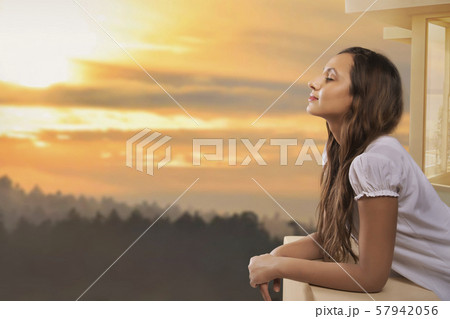 Portrait of happy woman standing at open window Portrait of happy woman standing at open window 57942056