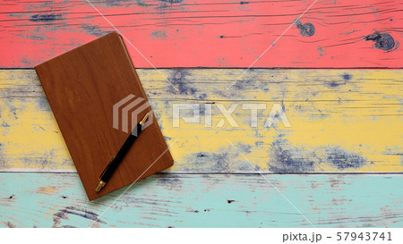 Note book with wooden cover, and a black ball pen on top of it. With empty space on the right. Note book with wooden cover, and a black ball pen on top of it. With empty space on the right. 57943741