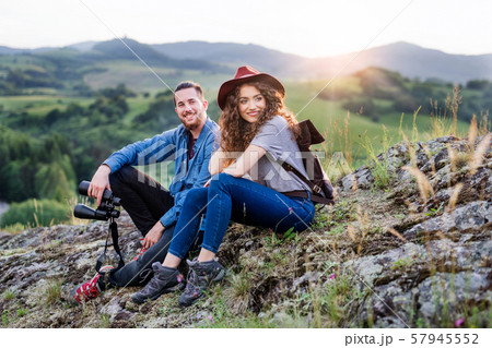 Young tourist couple travellers with binoculars hiking in nature, resting. Young tourist couple travellers with binoculars hiking in nature, resting. 57945552