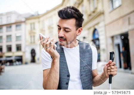 Young blind man with smartphone on street in city, making phone call. 57945675