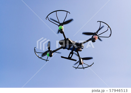 Flying drone or quad copter in blue sky. Flying drone or quad copter in blue sky. 57946513