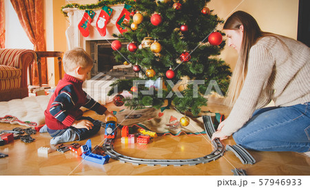 Toned photo of family playing with toy railroad on floor at living room on Christmas morning Toned photo of family playing with toy railroad on floor at living room on Christmas morning 57946933